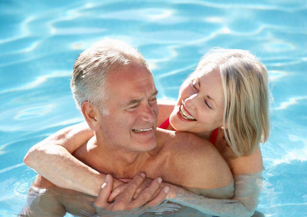 Resident smiling couple holding each other on a sunny day in the swimming pool in El Mirage, Arizona.