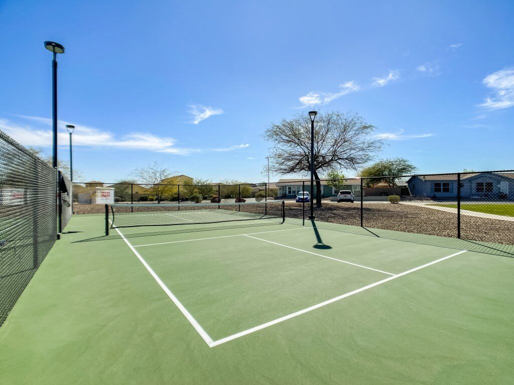 Outdoor tennis court at a fenced area with pole lamps at the side